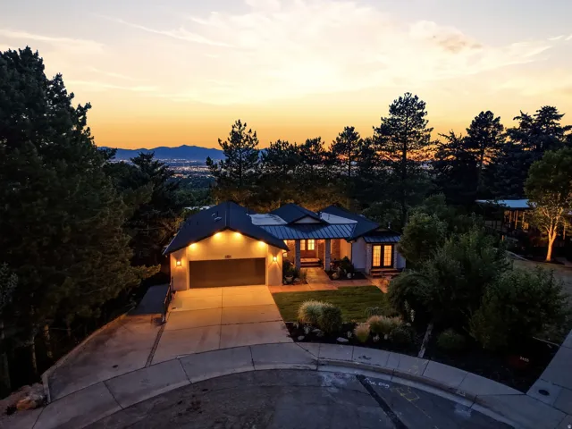 Contemporary residence featuring a paved driveway, attached garage, and prominent landscape lighting