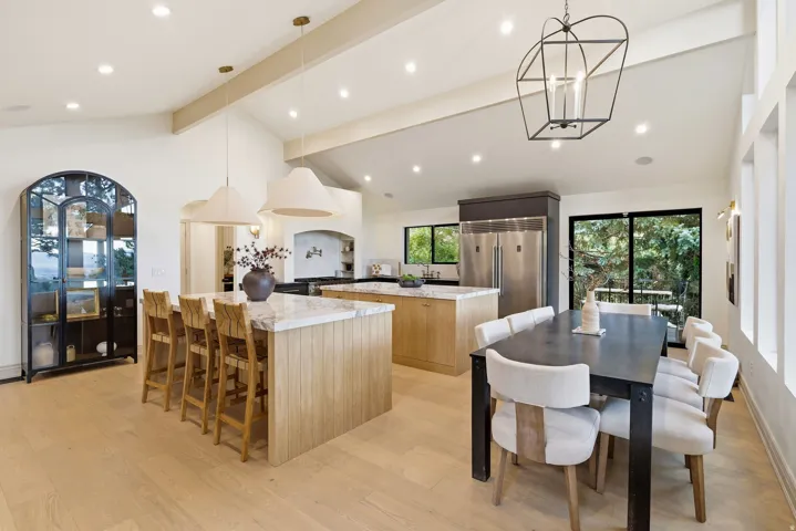Vaulted ceilings with exposed beams, recessed lighting, and light wood-finish flooring