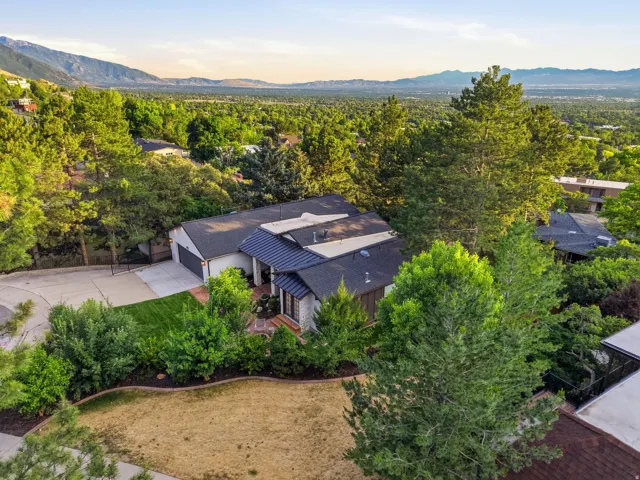 Contemporary residence featuring a dark shingle roof, attached two-car garage, and a light-colored stone facade