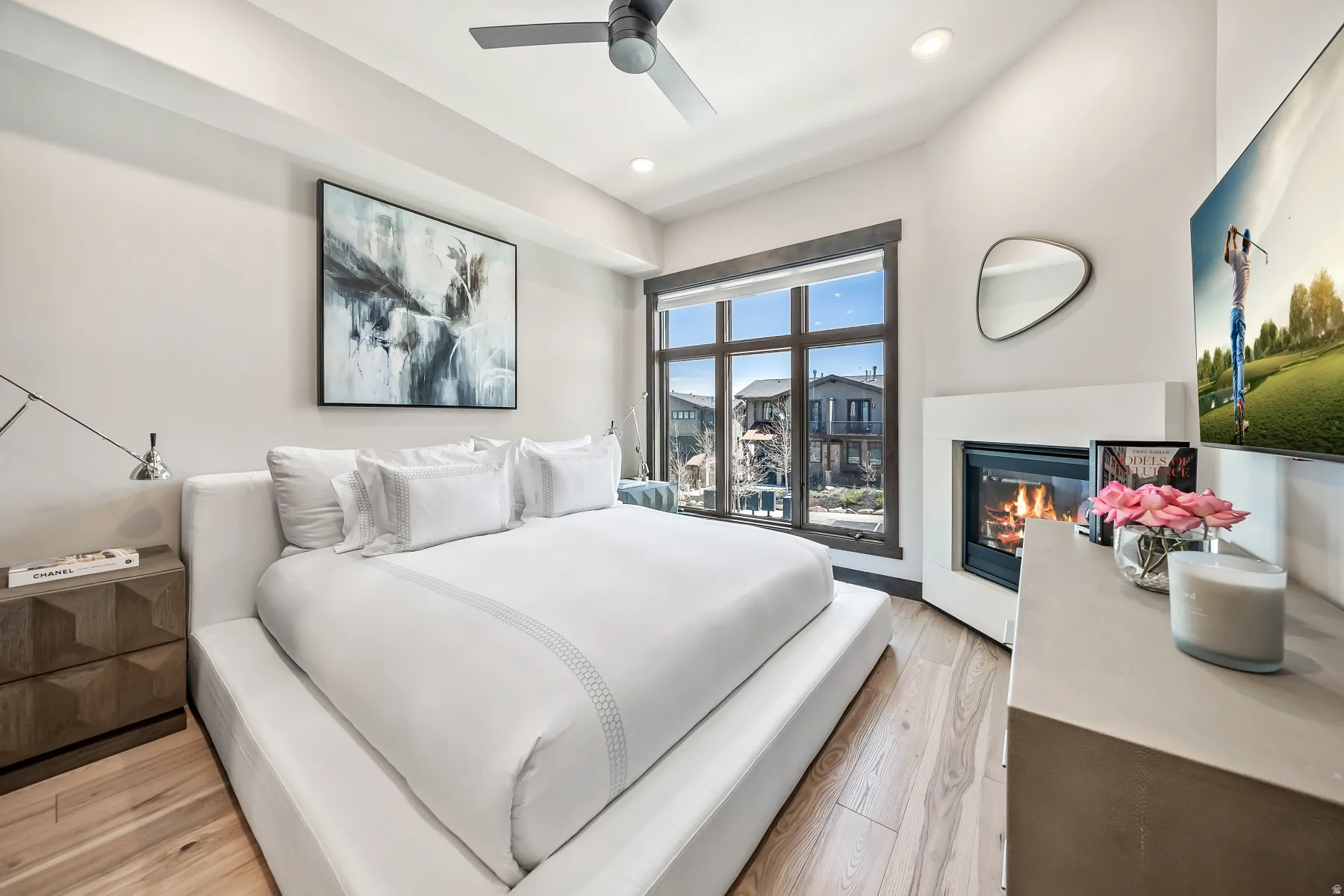 Light wood-finish flooring complements a corner fireplace and large windows