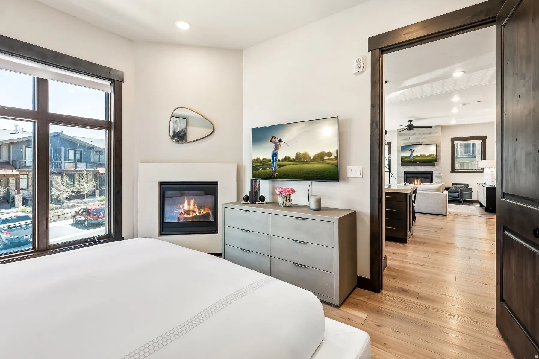 Interior space featuring a built-in fireplace with a light-toned surround, a large window with dark wood framing, and wood-finish flooring