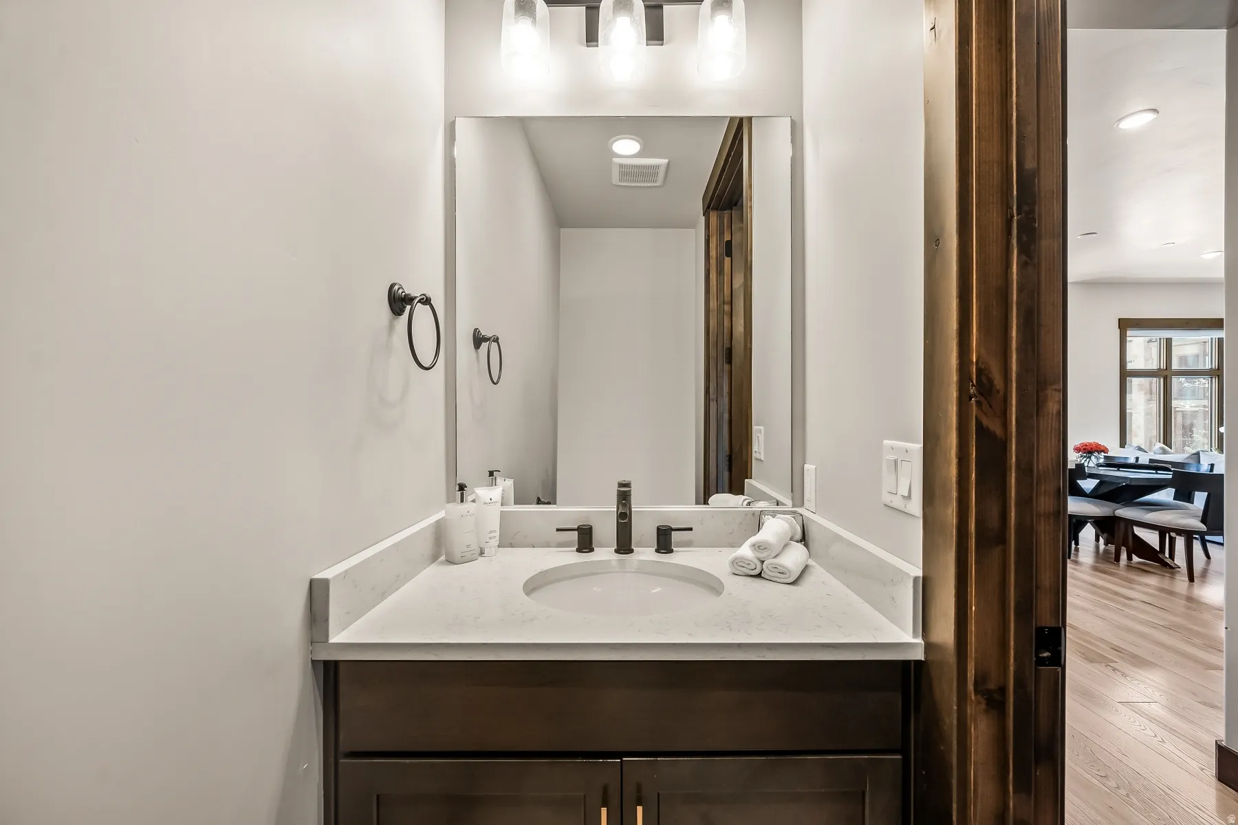 Single vanity featuring a light-toned countertop with an integrated sink, matte black faucet, and dark wood-finish cabinetry