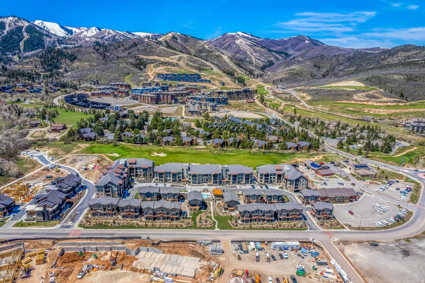Expansive aerial perspective showcasing a master-planned community with varied architectural styles, surrounded by mountainous terrain