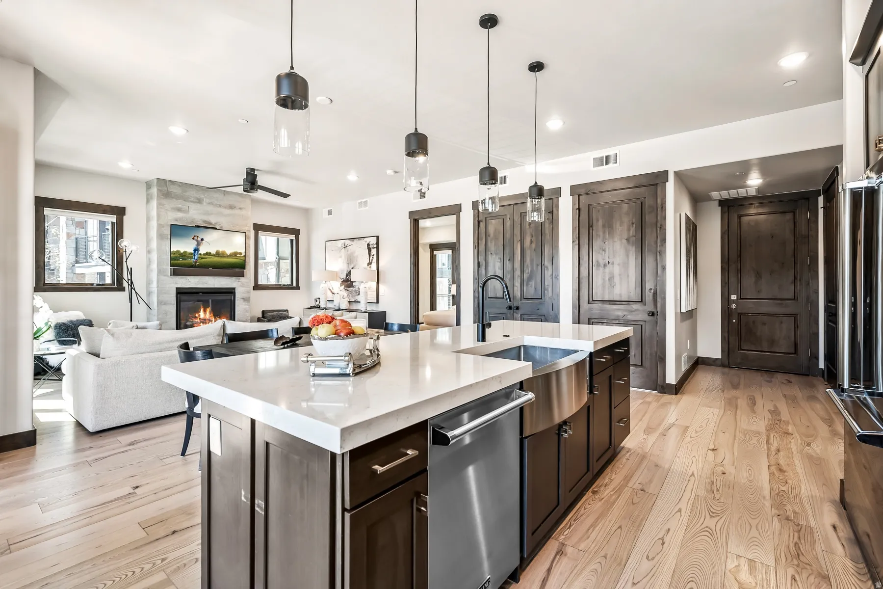 Kitchen island with a light-toned countertop, integrated stainless steel farmhouse sink, and a dishwasher