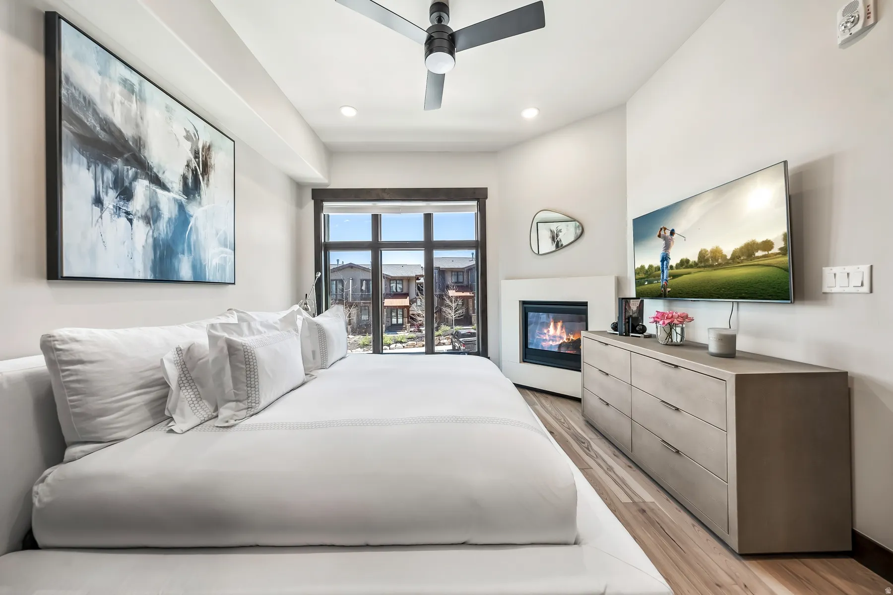 Modern bedroom featuring a built-in fireplace, large glass patio door, and wood-finish flooring