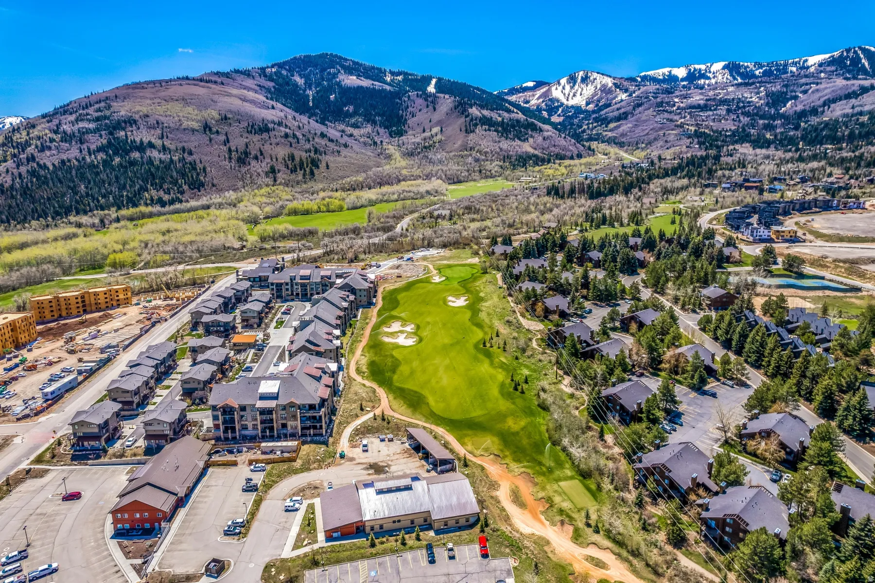 Expansive residential area featuring a golf course, mountain backdrop, and multiple housing types including multi-story residences and single-family homes