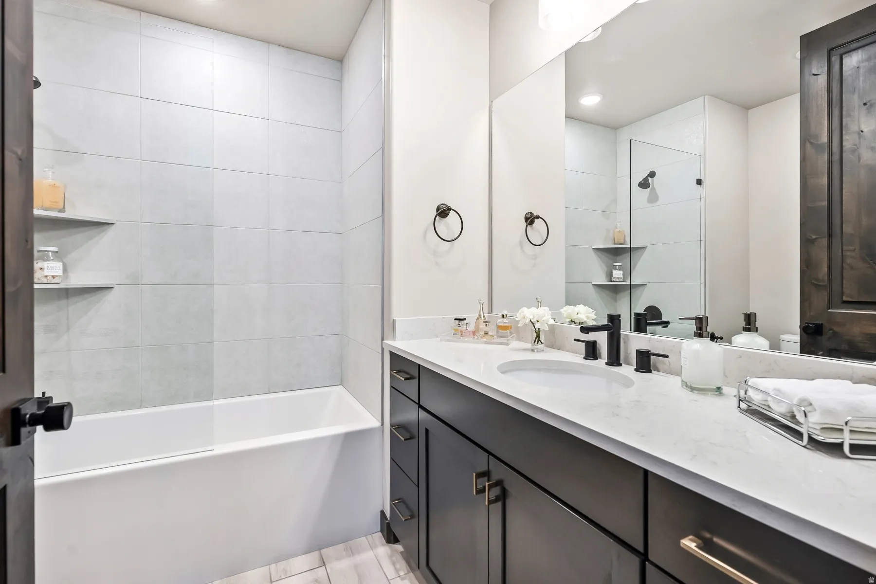 Bathroom featuring a tub with light-toned tiled surround and built-in shelving