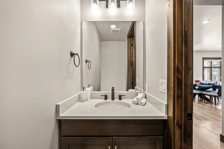 Single vanity featuring a light-toned countertop with an integrated sink, matte black faucet, and dark wood-finish cabinetry