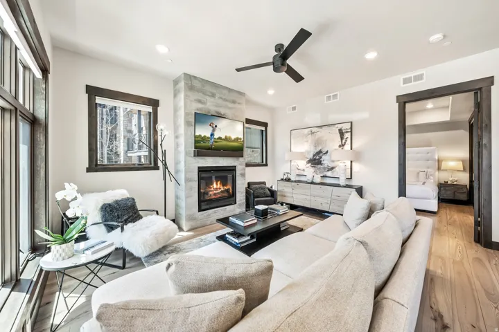 Spacious living area featuring light wood-finish flooring, a stone-clad fireplace with a built-in television, and recessed lighting