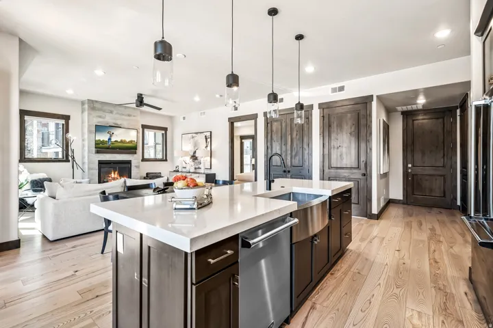 Kitchen island with a light-toned countertop, integrated stainless steel farmhouse sink, and a dishwasher