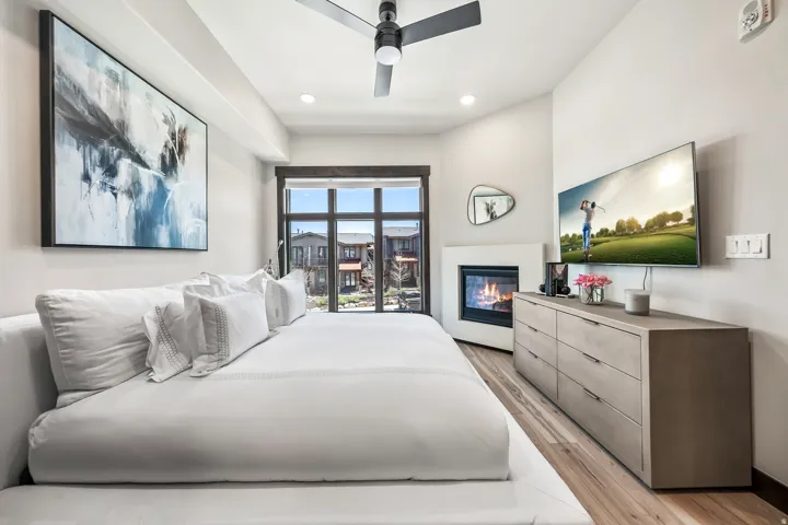 Modern bedroom featuring a built-in fireplace, large glass patio door, and wood-finish flooring
