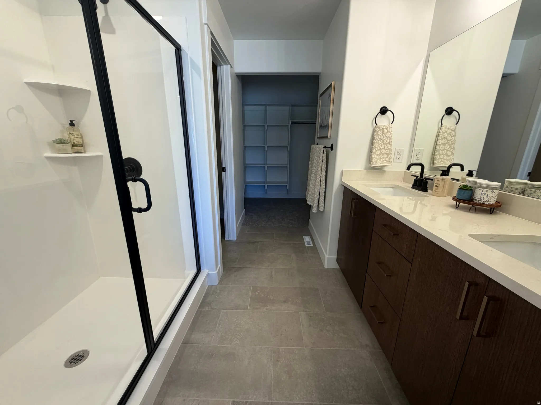 Spacious bathroom featuring a dual-sink vanity with light-toned countertops and dark wood-finish cabinetry