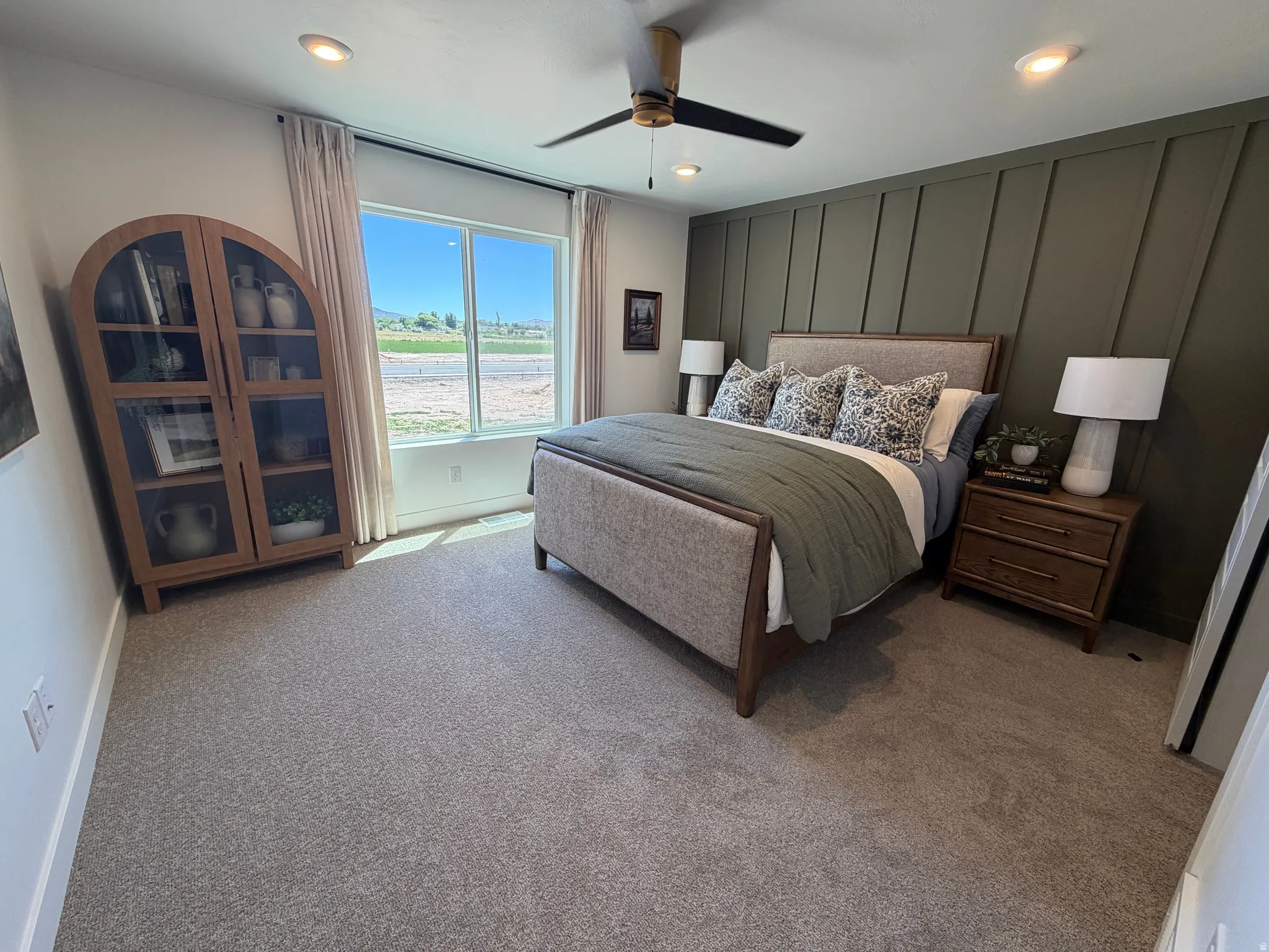 Bedroom featuring a statement accent wall with vertical paneling, light gray carpeting, and a large window with white trim