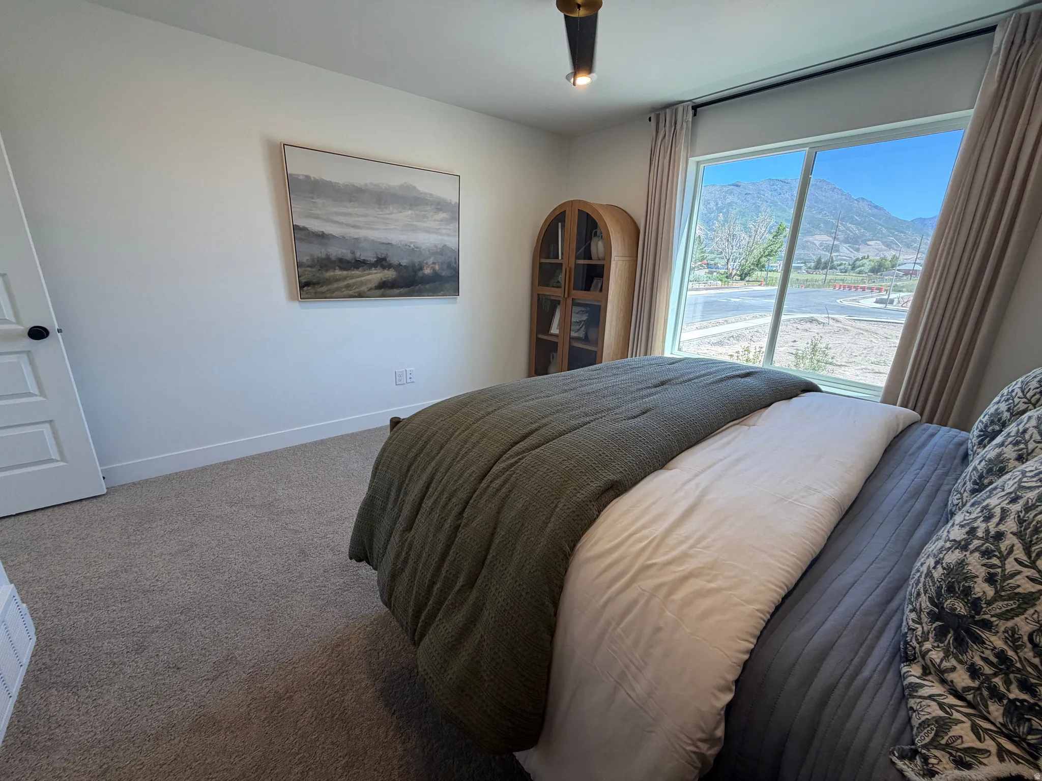 Room featuring a large window with mountain scenery, neutral-toned carpeting, white walls, and a modern ceiling light fixture
