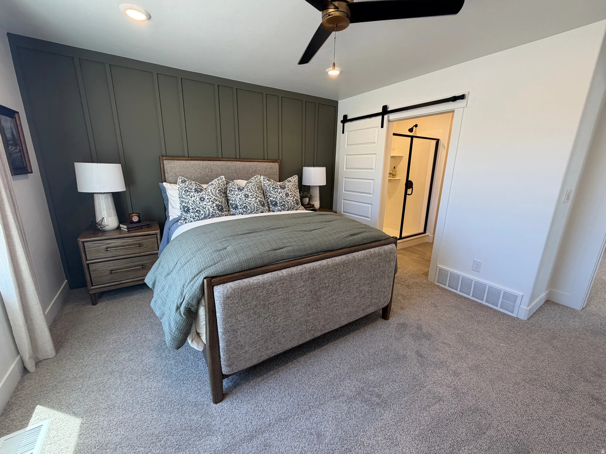 Bedroom featuring a dark green accent wall with vertical paneling