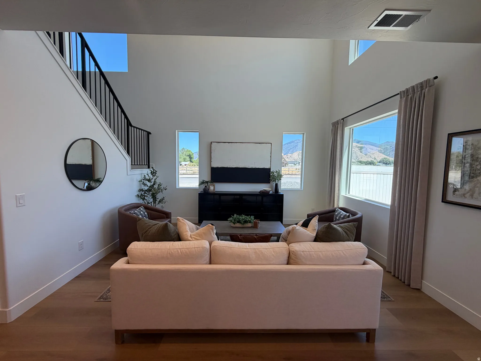 Spacious living area featuring high ceilings, wood-finish flooring, and large windows with surrounding scenery