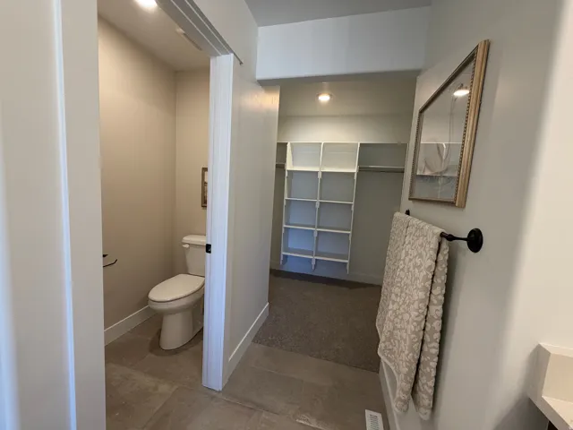 Walk-in closet with built-in shelving, plush carpeting, and recessed lighting