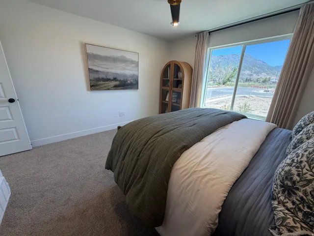Room featuring a large window with mountain scenery, neutral-toned carpeting, white walls, and a modern ceiling light fixture