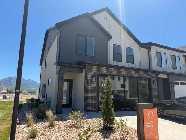 Contemporary multi-story exterior featuring a mix of horizontal and vertical siding, brick accents, dark-framed windows, and a covered entry
