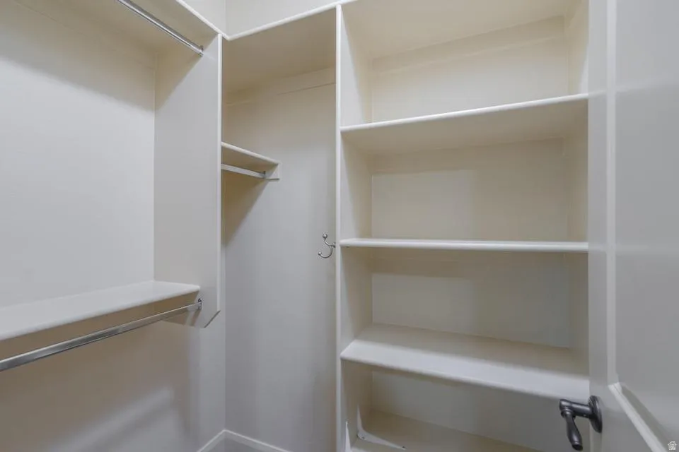 Walk-in closet featuring multiple shelving units and chrome hanging rods