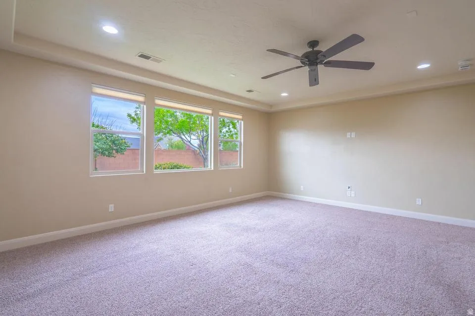 Spacious room featuring three large windows, recessed ceiling lighting, a ceiling fan, crown molding, and neutral-toned carpeting