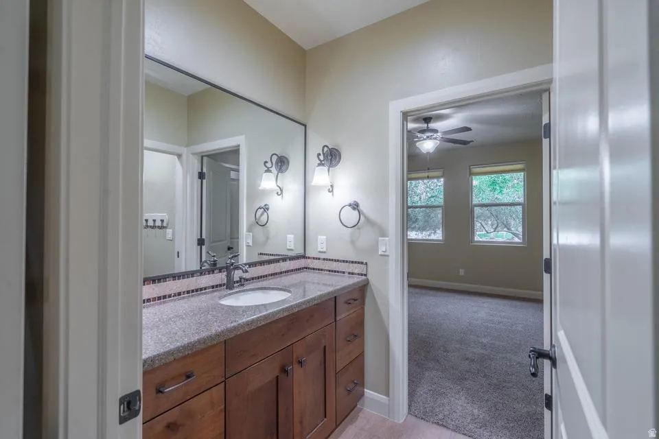 Bathroom vanity featuring a single basin, granite-look countertop, and mosaic tile backsplash