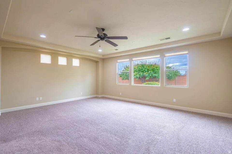 Spacious interior featuring neutral carpeting and a tray ceiling with recessed lighting