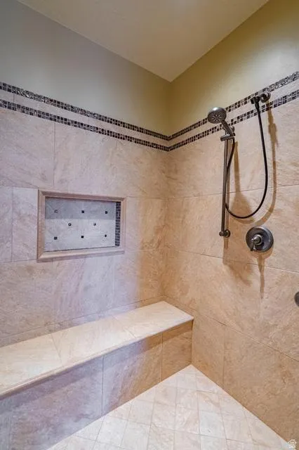 Tiled shower enclosure featuring a built-in bench, recessed niche, and a handheld shower fixture