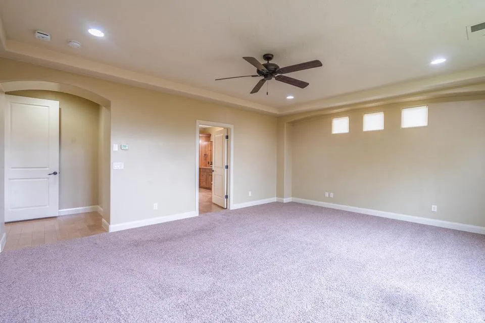 Spacious interior room featuring plush carpeting, recessed lighting, and a ceiling fan