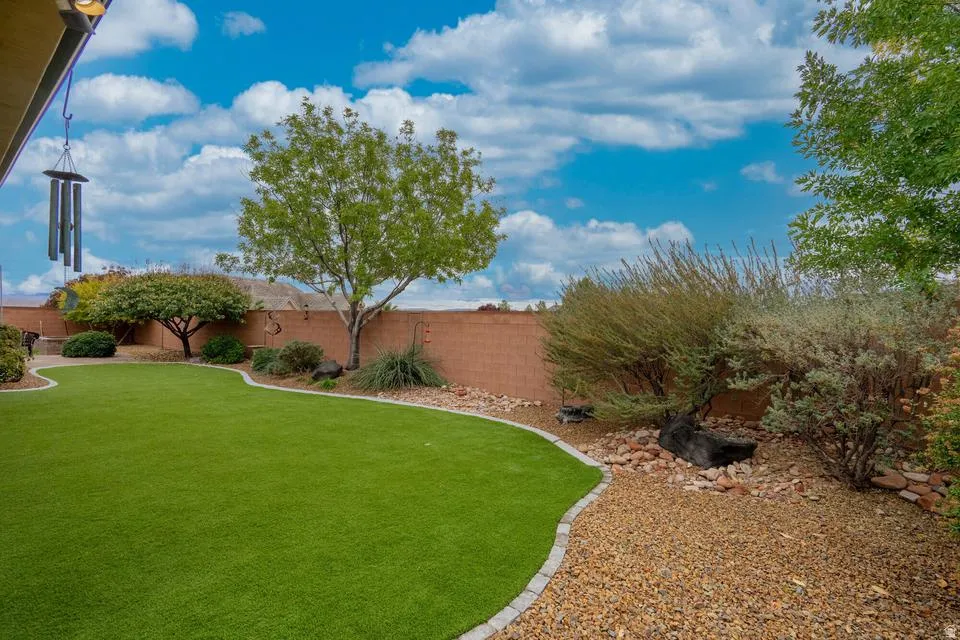 Expansive backyard featuring a lush green lawn, mature trees, and decorative gravel landscaping