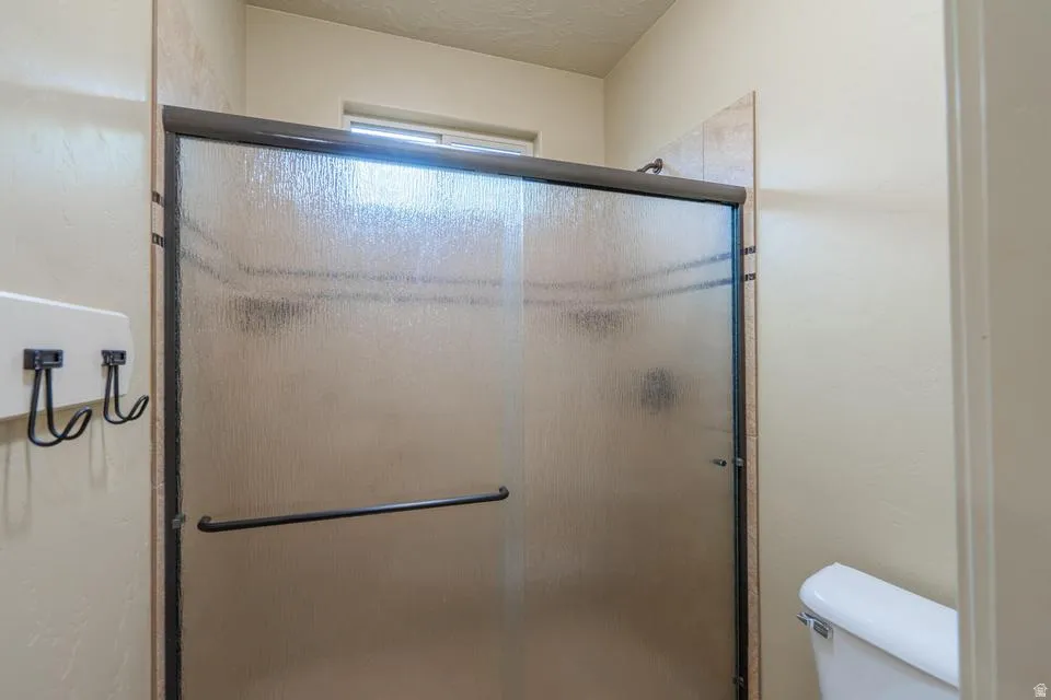 Enclosed shower stall with textured glass doors, dark trim, and a built-in shower head