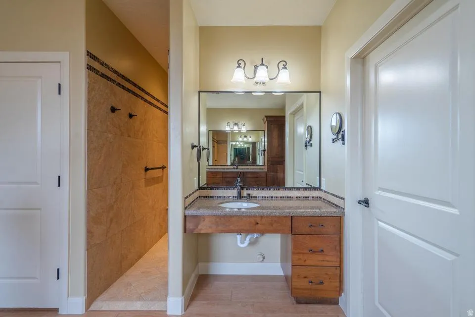 Vanity area featuring a built-in wood-finish cabinet with drawers, a granite-style countertop, and a rectangular undermount sink