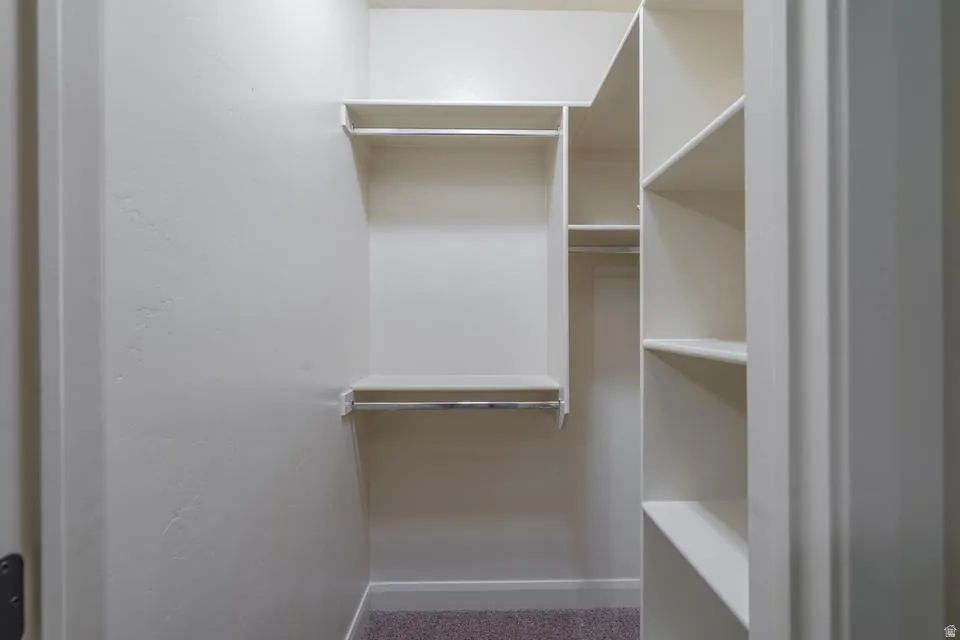 Walk-in closet featuring white painted walls and multi-level shelving