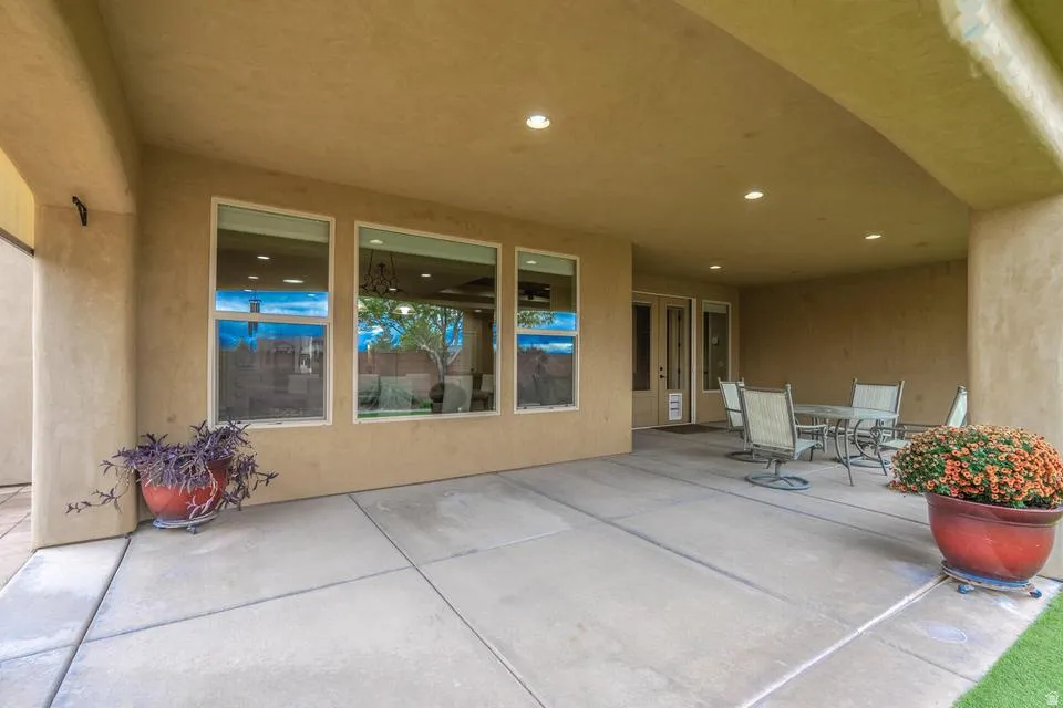 Expansive covered patio featuring a concrete slab, recessed lighting, stucco archways, and large windows