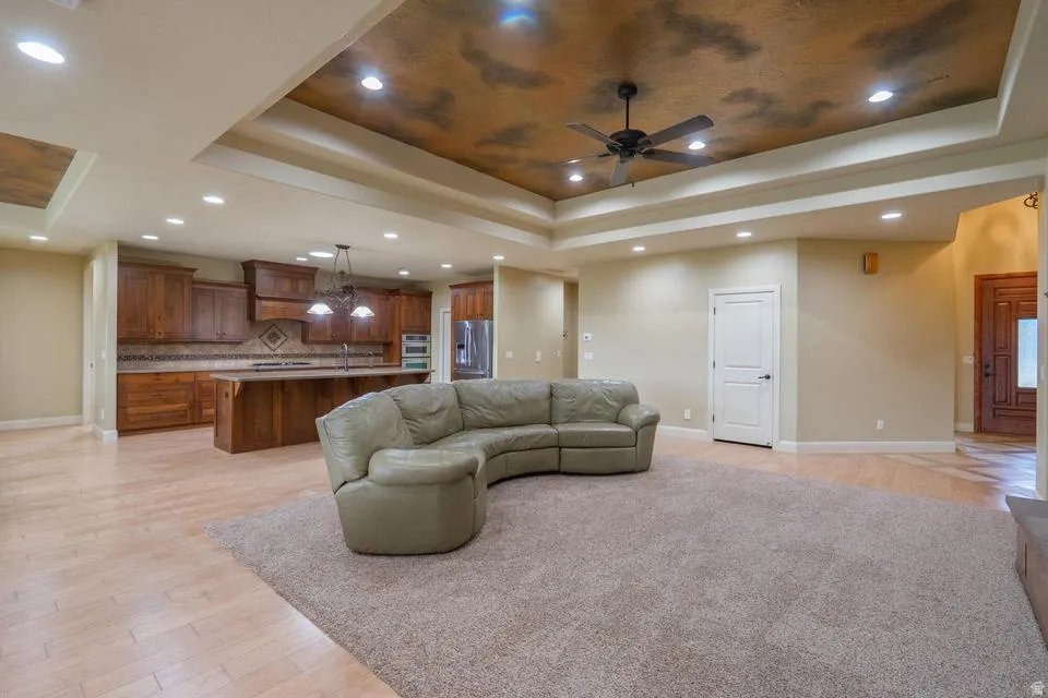 Open-concept living space featuring a tray ceiling with recessed lighting and a ceiling fan