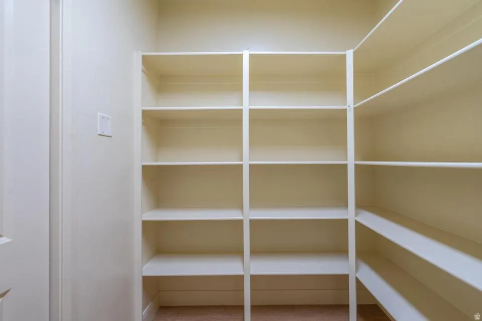 Walk-in pantry featuring extensive built-in shelving, light-colored walls, and a light switch on the wall
