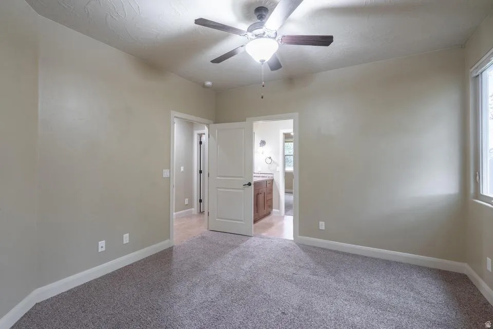 Carpeted room with neutral wall tones and a ceiling fan with integrated lighting