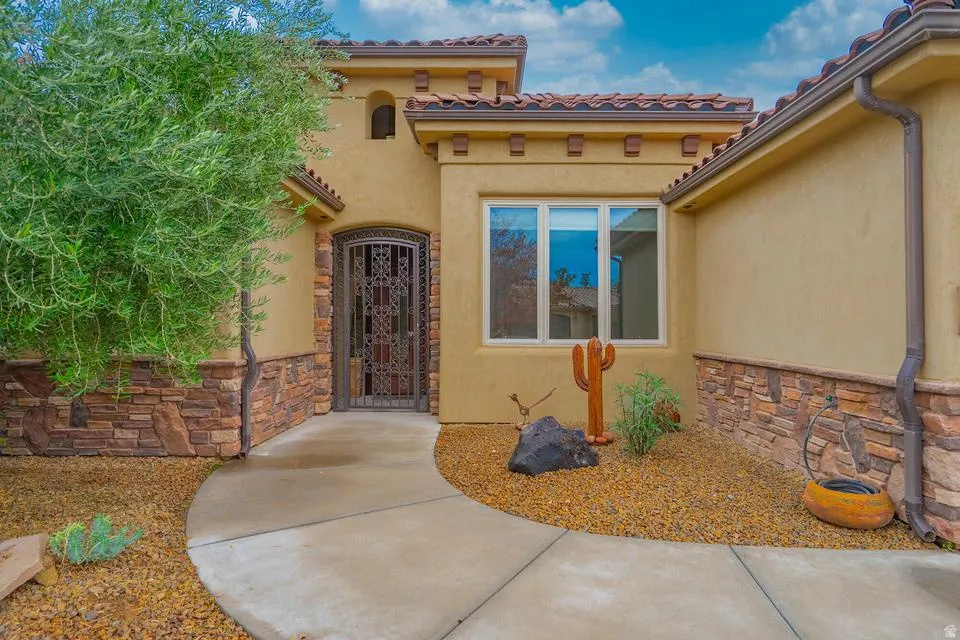 Stucco exterior with a terracotta tile roof, accented by a decorative iron gate entrance