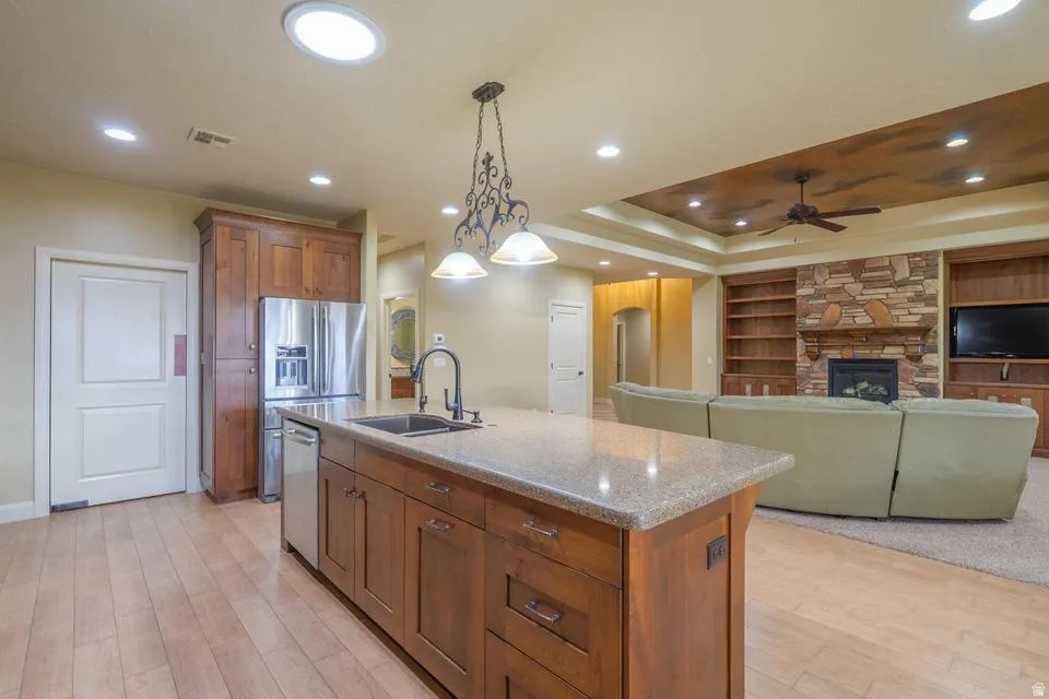 Kitchen island featuring a built-in sink, granite countertop, and pendant lighting