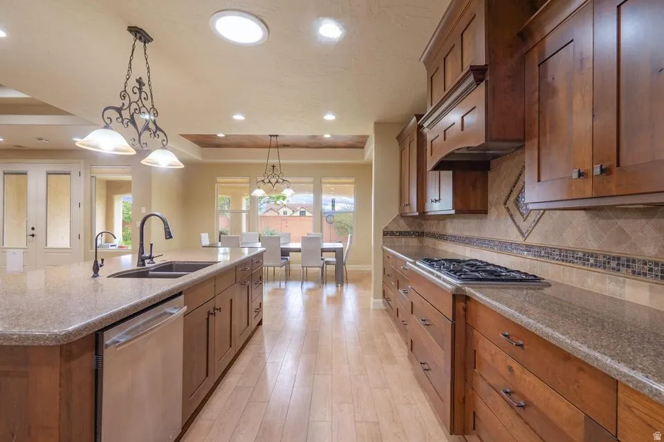 Kitchen featuring wood cabinetry, stone countertops, stainless steel appliances, and wood-finish flooring