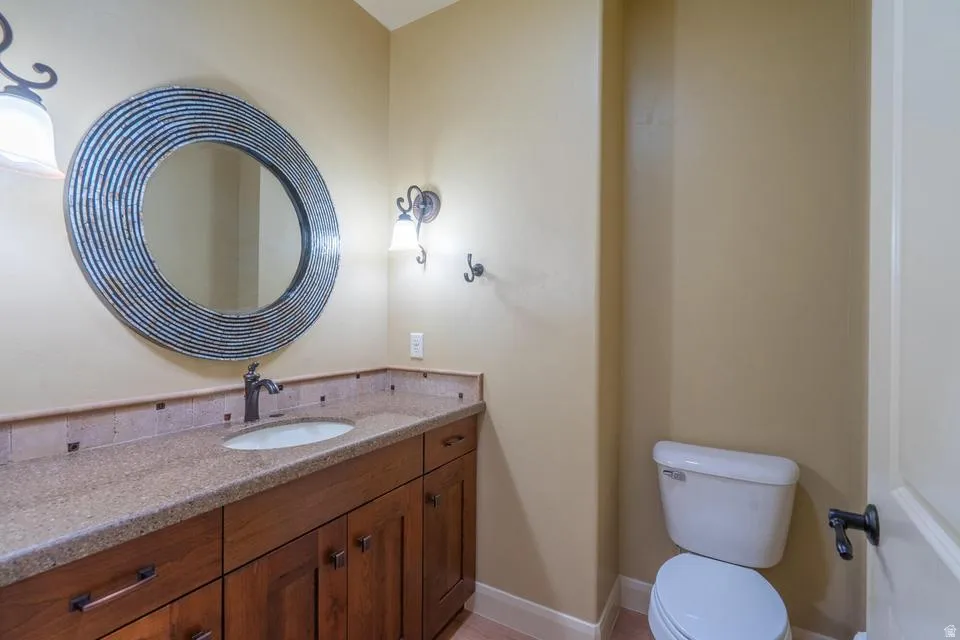 Vanity with a granite countertop, undermount sink, and wood cabinetry