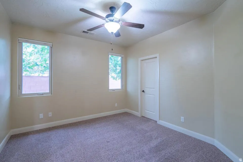Carpeted room with a ceiling fan light fixture