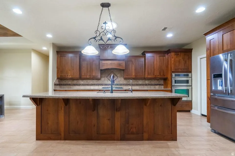 Kitchen featuring a large wood-finish island with a stone-finish countertop, pendant lighting, recessed ceiling lighting, and a full suite of stainless steel appliances