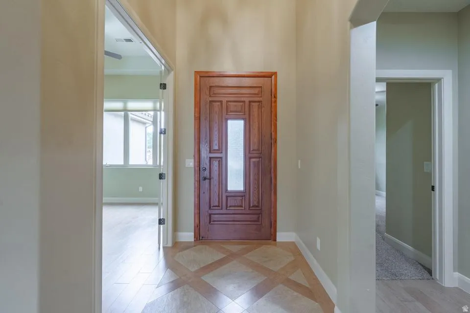 Grand entry featuring a paneled wood door with frosted glass insert, neutral wall tones, and a tiled floor with a diamond pattern
