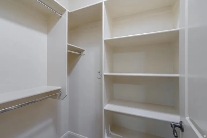 Walk-in closet featuring multiple shelving units and chrome hanging rods