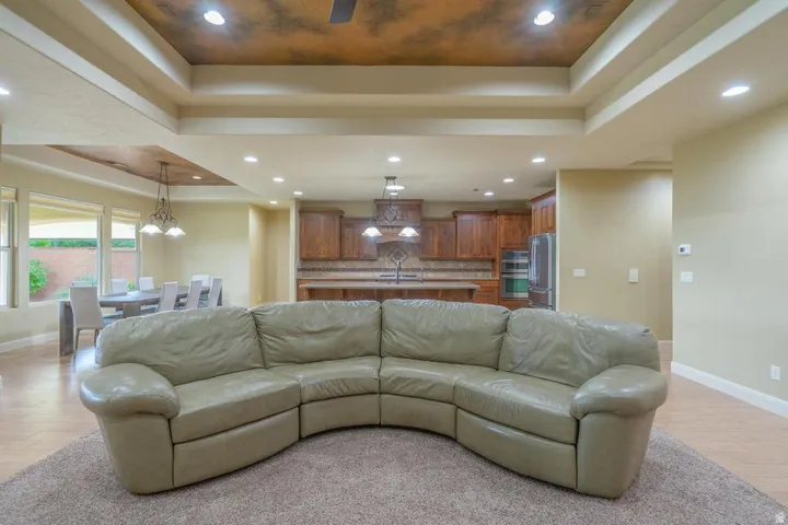 Open concept living area featuring a tray ceiling with recessed lighting, wood-finish flooring, and a kitchen with wood cabinetry and built-in appliances
