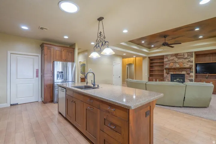 Kitchen island featuring a built-in sink, granite countertop, and pendant lighting