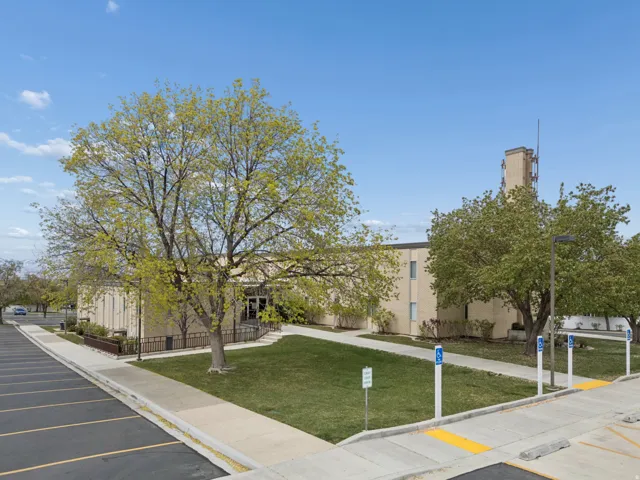 Masonry building with mature trees and expansive parking lot with designated accessible parking spaces.
