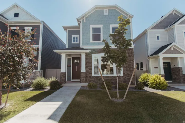 Two-story dwelling featuring a light blue shake siding and dark brick facade