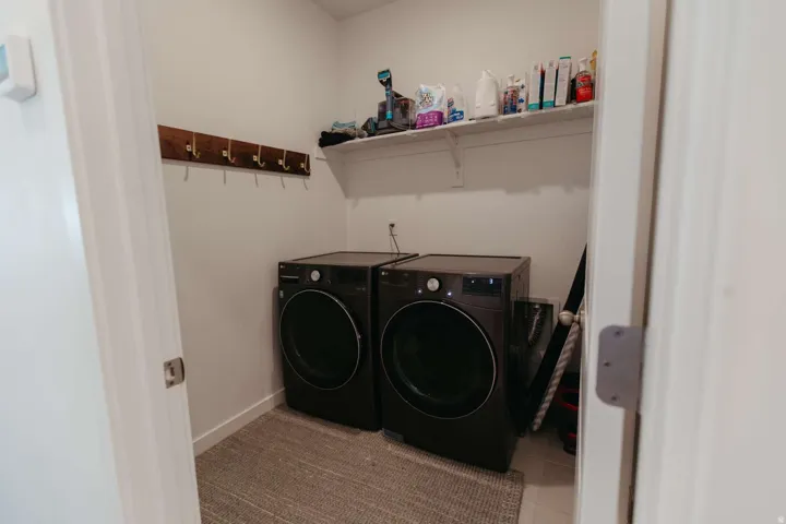 Dedicated laundry area featuring a built-in wood coat rack with metal hooks and an overhead storage shelf